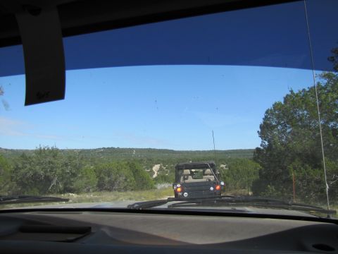 1995 Ford Bronco - Driving on a dirt road behind a Jeep Wrangler with a clear blue sky overhead.