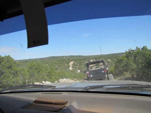 1995 Ford Bronco - Two vehicles navigate a , off-road trail through a wooded, hilly landscape.