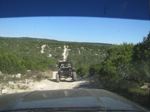 1995 Ford Bronco - A black Jeep Wrangler navigates a dusty trail in a scenic, undeveloped area.