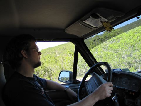 1995 Ford Bronco - A man drives a vehicle through a scenic, green, hilly area, with the interior of the car visible.