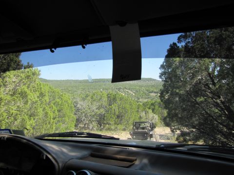 1995 Ford Bronco - View from inside a vehicle looking at another off-road vehicle ahead on a dusty trail.
