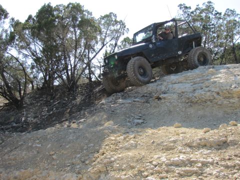 1995 Ford Bronco - A driver navigates a challenging rocky path in a modified off-road vehicle.