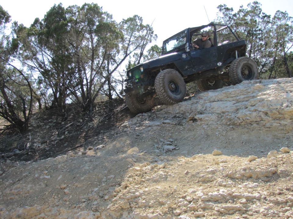 Dark green off-road vehicle climbing rocky terrain
