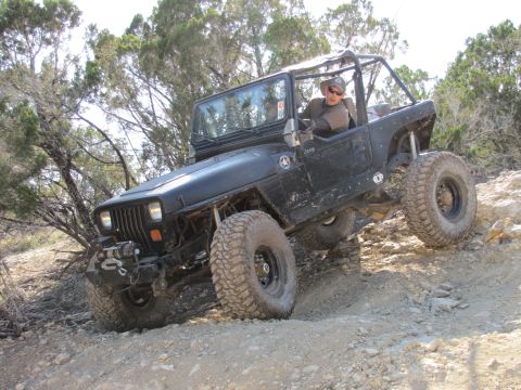 1995 Ford Bronco - A black Jeep Wrangler navigates a challenging, rocky off-road trail.