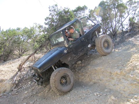 1995 Ford Bronco - A black Jeep Wrangler navigates a steep, rocky incline with two occupants.