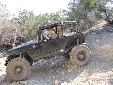 1995 Ford Bronco - Jeep Wrangler TJ navigating a challenging off-road course with steep inclines and loose terrain.