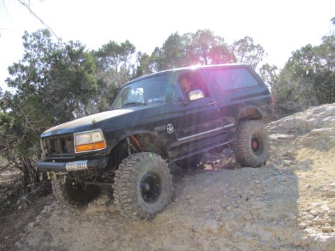 1995 Ford Bronco - This 1995 Ford Bronco navigates a challenging off-road trail with large tires and a lifted suspension.