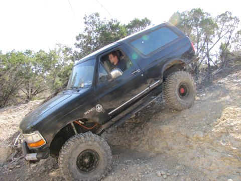 1995 Ford Bronco - A 1995 Ford Bronco navigates a challenging off-road trail, demonstrating its capability on rough terrain.