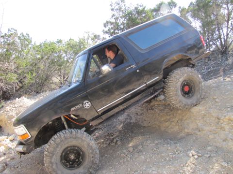 1995 Ford Bronco - A black 1995 Ford Bronco navigates a steep, rocky incline during an off-road excursion.