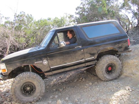 1995 Ford Bronco - 1995 Ford Bronco navigating a steep, rocky trail during an off-road excursion.