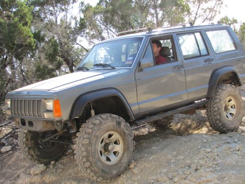 1995 Ford Bronco - A lifted 1992 Ford Bronco with off-road tires navigates uneven terrain.