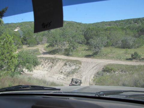 1995 Ford Bronco - Driving on a dusty, unpaved road through a sparsely vegetated, hilly area under a clear blue sky.