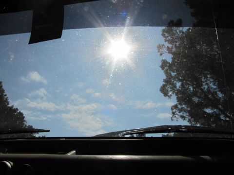 1995 Ford Bronco - Looking out the windshield on a sunny day with clouds and trees.