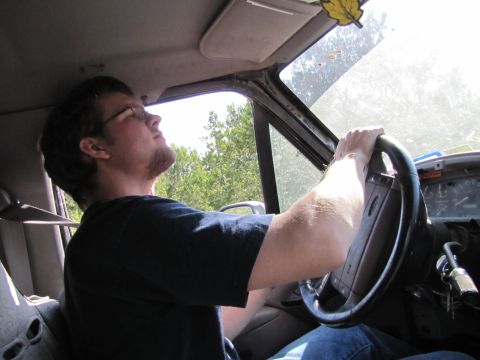 1995 Ford Bronco - Driver looks up towards the sun while holding the steering wheel inside a vehicle.