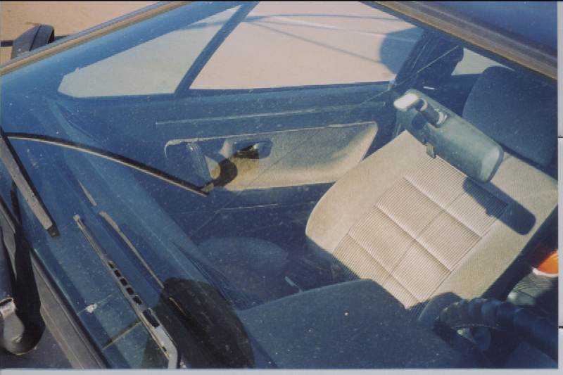 Tan cloth interior of a dark blue car viewed through the windshield