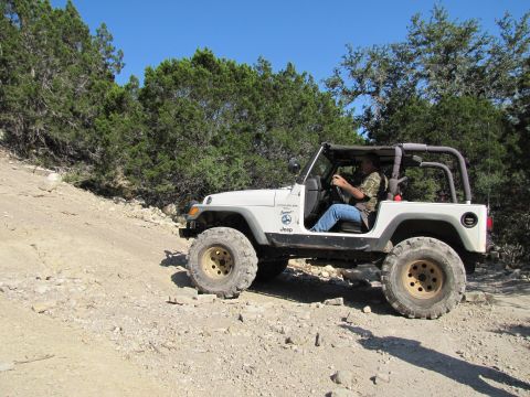 1995 Ford Bronco - Jeep Wrangler navigating a rough off-road trail.