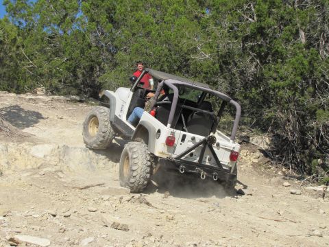 1995 Ford Bronco - Jeep Wrangler navigating a challenging off-road trail with steep, rocky terrain.