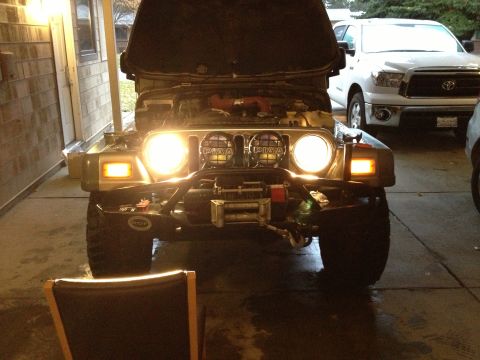 2005 Jeep Wrangler - Front view of a Jeep Wrangler with its hood open, aftermarket lights and a winch. Another vehicle is visible in the background.