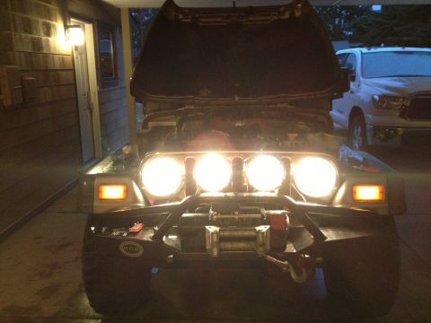 2005 Jeep Wrangler - Front view of a 2005 Jeep Wrangler with its hood open and auxiliary lights illuminated, parked next to another vehicle.