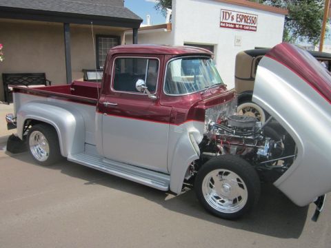 1991 Ford LTD Crown Victoria - A two-tone maroon and silver 1956 Ford F-100 pickup truck is displayed with its hood open, revealing a chrome engine.