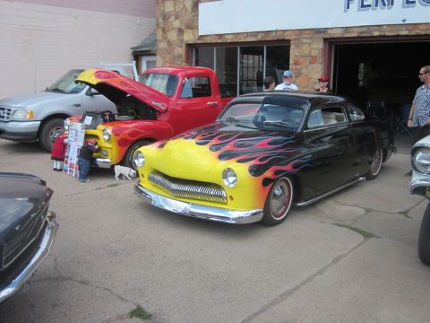 1991 Ford LTD Crown Victoria - A custom hot rod with flame paintwork is displayed at an outdoor car show.