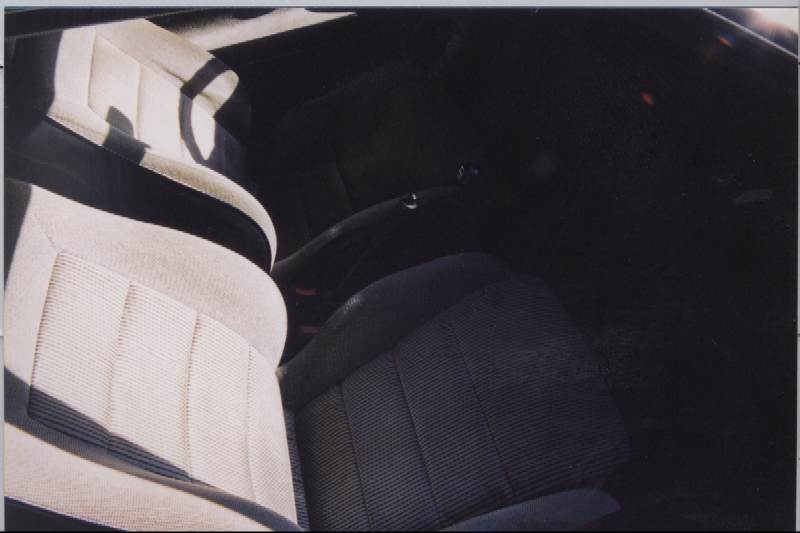 Front bucket seats with tan and gray cloth upholstery and seatbelts