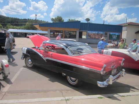 1991 Ford LTD Crown Victoria - Classic 1956 Ford Fairlane Crown Victoria at a car show, hood up, parked beside another vintage vehicle.