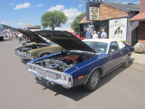 1991 Ford LTD Crown Victoria - Two classic cars are displayed with hoods up at an outdoor car show.