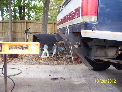 1990 Ford Bronco - Rear view of a vehicle's bumper and suspension system, with tools and equipment visible in the background.