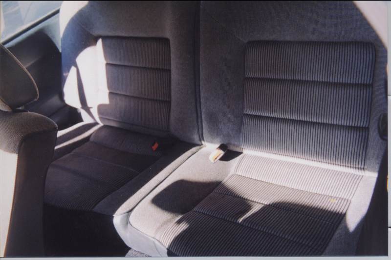 Gray striped cloth rear seats of a two-door car seen through the open door