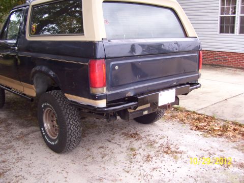 1990 Ford Bronco - The rear of a Ford Bronco shows an aftermarket bumper and a two-tone paint scheme.