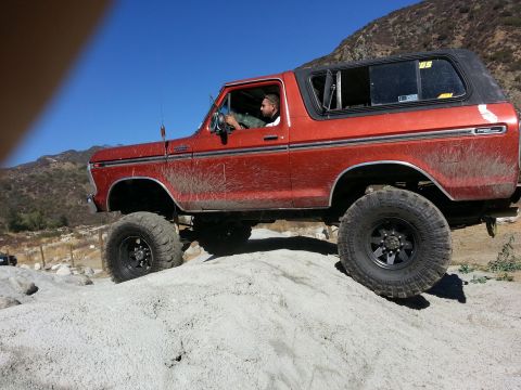 1978 Ford Bronco - This lifted Ford Bronco navigates a rocky incline under a clear blue sky.