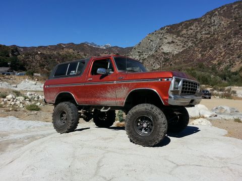 1978 Ford Bronco - This lifted 1978 Ford Bronco is parked on a large rock with mountains in the background under a clear blue sky.