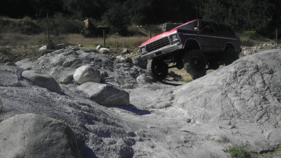 Red and black off-road SUV climbing a rocky incline