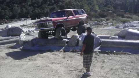 1978 Ford Bronco - A red 1978 Ford Bronco navigates a challenging obstacle course with large tires.