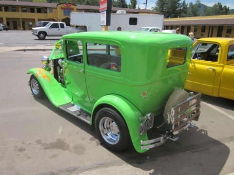 1991 Ford LTD Crown Victoria - A bright green hot rod sedan is parked next to a yellow pickup truck at an outdoor car show.