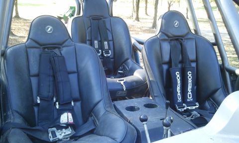 1967 Ford Mustang - The interior of a buggy features three black Corbeau racing seats with multi-point harnesses and a central console with cup holders.