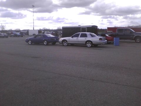 2003 Ford Crown Victoria - A silver sedan is parked next to a blue coupe at an outdoor event.