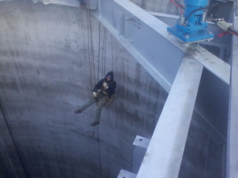 Person rappelling down concrete structure with steel beams overhead