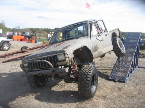 1987 Jeep Comanche - Modified 1987 Jeep Comanche pickup truck attempting to climb a ramp during an off-road event.
