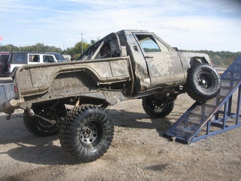 1987 Jeep Comanche - A heavily modified 1987 Jeep Comanche is shown climbing a ramp during an off-road event.