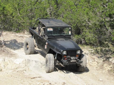 1995 Ford Bronco - A black Jeep Wrangler navigates a challenging rocky terrain during an off-road excursion.