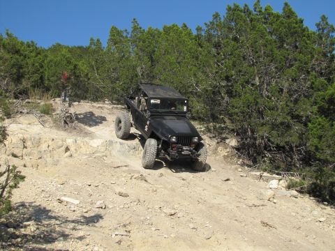 1995 Ford Bronco - Jeep Wrangler navigating challenging off-road terrain on a sunny day.