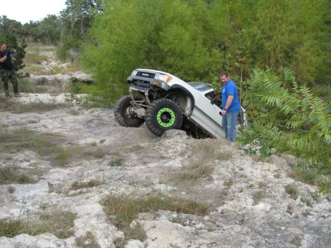 1995 Ford Bronco - A modified Toyota 4Runner is stuck on a rocky incline with a person observing the situation.