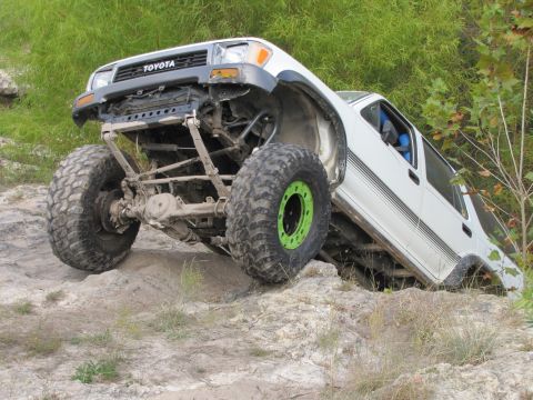 1995 Ford Bronco - A white Toyota truck navigates a challenging rocky obstacle course.