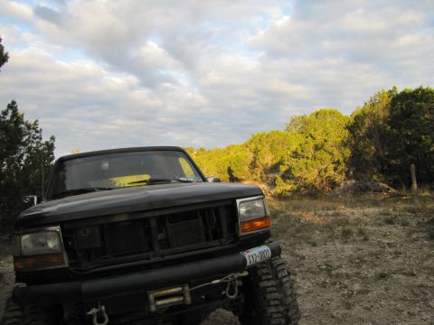 1995 Ford Bronco - A black Ford truck sits in a dry, brushy landscape under a cloudy sky.