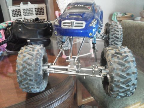 1985 Ford Bronco - A blue remote control monster truck sits on a table, its large tires and suspension system prominently displayed.