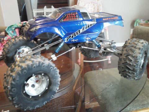 1985 Ford Bronco - A blue Pro-Line remote control monster truck is displayed on a glass table.