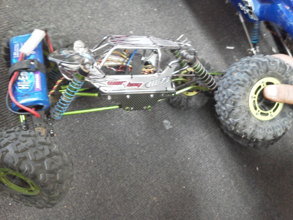 RC rock crawler with chrome body, green suspension, and a blue battery pack. Text on body reads 'GIANT HOBBY HEZ'
