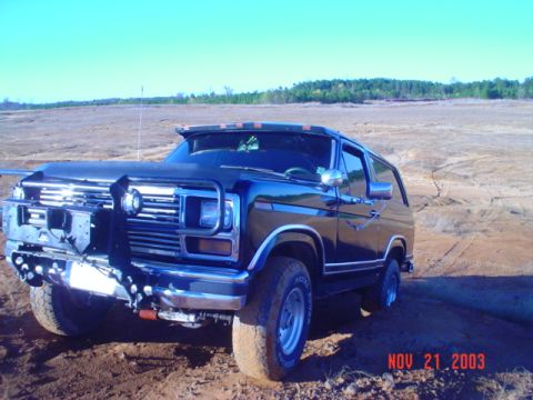 1986 Ford Bronco - This dark blue SUV, likely from the early 1980s, is equipped with extensive off-road modifications.